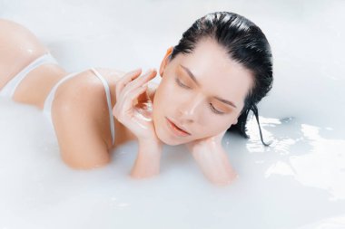 Süt banyosundaki yumuşak beyaz parlayan kadın mankeni kapat. Reklamcılık için telif hakkı. Güzellik, moda, tarz, vücut bakımı konsepti.