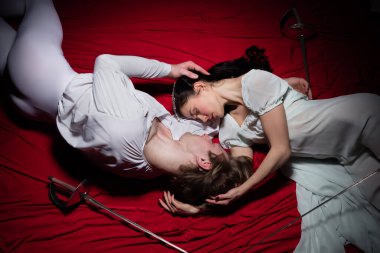 Genç ve zarif bale dansçıları klasik hareketlerde kırmızı bez üzerinde dalgalanan arka planda. Sanat, hareket, eylem, esneklik, ilham kavramı.