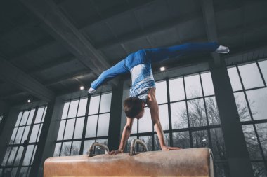Spor salonunda küçük bir erkek jimnastikçi, esnek ve aktif. Kafkasyalı formda küçük bir çocuk, spor giyimli bir sporcu güç ve denge egzersizleri yapıyor..