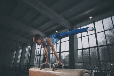 Spor salonunda küçük bir erkek jimnastikçi, esnek ve aktif. Kafkasyalı formda küçük bir çocuk, spor giyimli bir sporcu güç ve denge egzersizleri yapıyor..