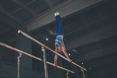Spor salonunda küçük bir erkek jimnastikçi, esnek ve aktif. Kafkasyalı formda küçük bir çocuk, spor giyimli bir sporcu güç ve denge egzersizleri yapıyor..