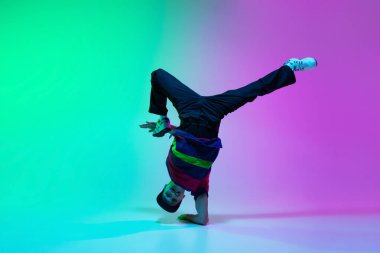 Güzel sporcu çocuk neon ışıklı dans salonunda renkli arka planda hip-hop dansı yapıyor..