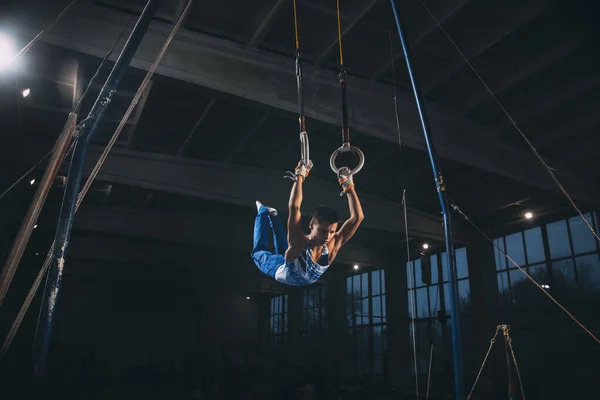 Little male gymnast training in gym, flexible and active. Caucasian fit little boy, athlete in sportswear practicing in exercises for strength, balance.