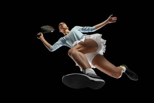 Női profi teniszező akcióban, mozgás elszigetelt fekete háttér, nézd meg alulról. A sport, a mozgás, az energia és a dinamika fogalma. — Stock Fotó