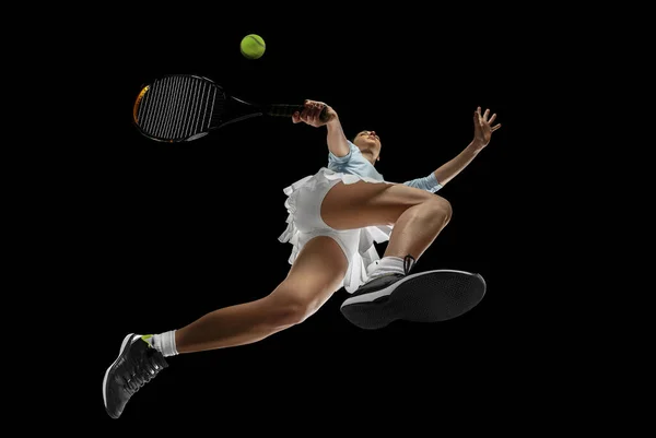 Женщина профессиональный теннисист в действии, движение изолированы на черном фоне, смотреть снизу. Концепция спорта, движения, энергии и динамики. — стоковое фото