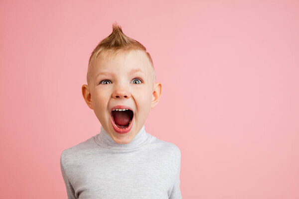 Happy boy isolated on pink studio background. Looks happy, cheerful, sincere. Copyspace. Childhood, education, emotions concept