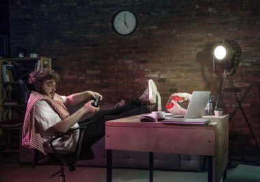 Genç, mutlu, beyaz bir adam bilgisayarla arkadaşlarıyla oynuyor..