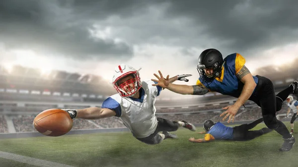 American football players in fight for goal at stadium in flashlights. Professional sportsman during game playing in action and motion. — Stock Photo, Image