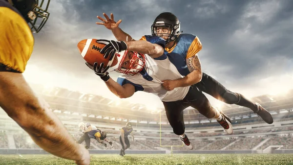 American football players in fight for goal at stadium in flashlights. Professional sportsman during game playing in action and motion. — Stock Photo, Image