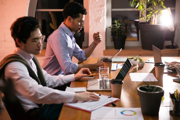 Colegas trabalhando juntos no escritório moderno usando dispositivos e gadgets durante a reunião criativa — Fotografia de Stock