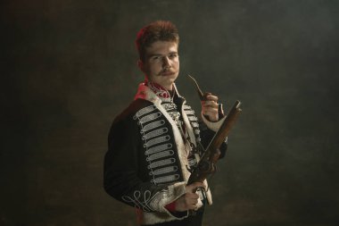 Kraliyet mensubu gibi giyinmiş genç adam koyu yeşil arka planda izole edilmiş. Retro stil, dönemin karşılaştırması. Tarihsel karakter gibi güzel bir erkek model, hükümdar, eski moda..