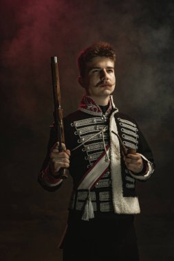 Kraliyet mensubu gibi giyinmiş genç adam koyu yeşil arka planda izole edilmiş. Retro stil, dönemin karşılaştırması. Tarihsel karakter gibi güzel bir erkek model, hükümdar, eski moda..