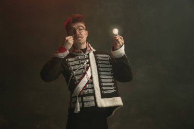 Kraliyet mensubu gibi giyinmiş genç adam koyu yeşil arka planda izole edilmiş. Retro stil, dönemin karşılaştırması. Tarihsel karakter gibi güzel bir erkek model, hükümdar, eski moda..