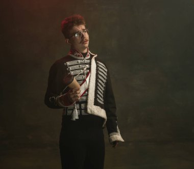 Kraliyet mensubu gibi giyinmiş genç adam koyu yeşil arka planda izole edilmiş. Retro stil, dönemin karşılaştırması. Tarihsel karakter gibi güzel bir erkek model, hükümdar, eski moda..