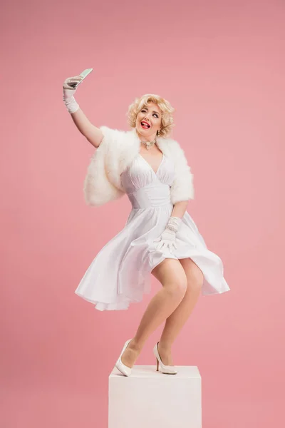 Retrato de jovem mulher de vestido branco sobre fundo rosa coral. Modelo feminina como atriz lendária. Preparem-se. Conceito de comparação de eras, moderno, moda, beleza. — Fotografia de Stock