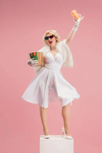 Portrait of young woman in white dress on coral pink background. Female model as a legendary actress. Pin up. Concept of comparison of eras, modern, fashion, beauty. — Stock Photo, Image