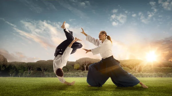 Mężczyzna i chłopiec, nauczyciel walczący z Aikido, trenujący sztuki walki na łące w letni wieczór — Zdjęcie stockowe