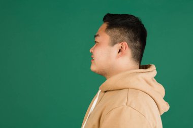 Asyalı adam portresi, yeşil stüdyo arka planında kopyalanmış.