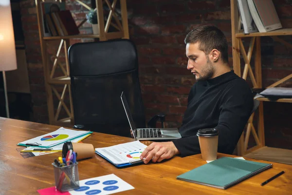 Hombre joven que trabaja en la oficina moderna utilizando dispositivos y aparatos. Realización de informes, análisis, tareas rutinarias de procesamiento — Foto de Stock