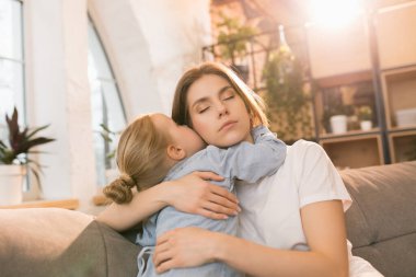 Aile zamanı. Anne ve kızı evde birlikte vakit geçiriyorlar, mutlu ve samimi görünüyorlar.