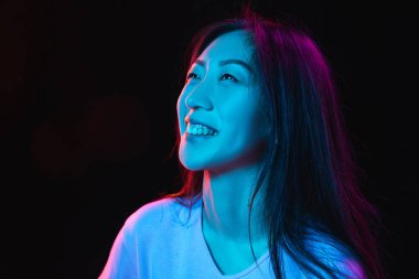 Asyalı genç kadınların Neon 'daki karanlık stüdyo arka planındaki portresi. İnsan duyguları kavramı, yüz ifadesi, gençlik, satış, reklam.
