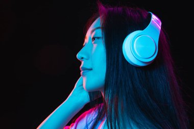 Asyalı genç kadınların Neon 'daki karanlık stüdyo arka planındaki portresi. İnsan duyguları kavramı, yüz ifadesi, gençlik, satış, reklam.