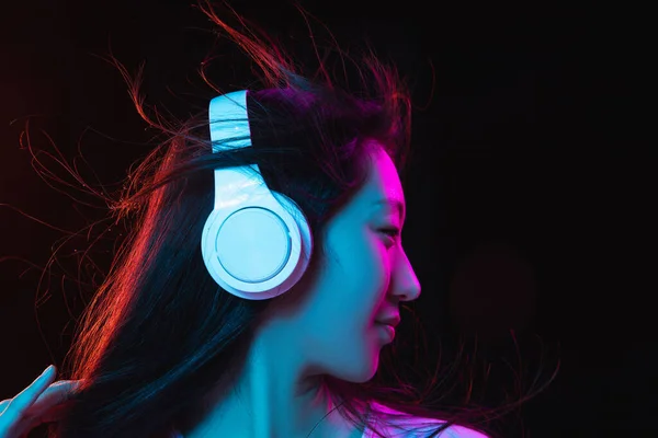 Asiatica giovane donna ritratto su sfondo scuro studio in neon. Concetto di emozioni umane, espressione facciale, gioventù, vendite, annuncio. — Foto Stock