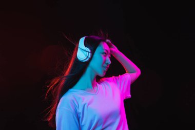 Asyalı genç kadınların Neon 'daki karanlık stüdyo arka planındaki portresi. İnsan duyguları kavramı, yüz ifadesi, gençlik, satış, reklam.