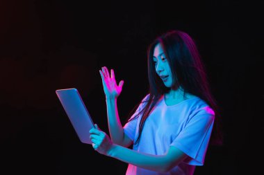 Asyalı genç kadınların Neon 'daki karanlık stüdyo arka planındaki portresi. İnsan duyguları kavramı, yüz ifadesi, gençlik, satış, reklam.