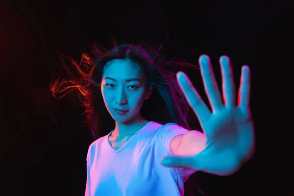 Asiático jovens mulheres retrato no escuro estúdio fundo em néon. Conceito de emoções humanas, expressão facial, juventude, vendas, anúncio. — Fotografia de Stock