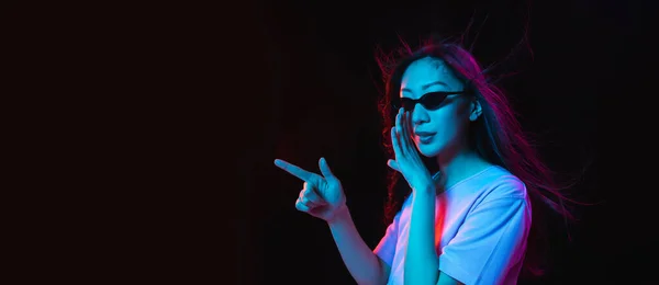 Aziatische jonge vrouwen portret op donkere studio achtergrond in neon. Concept van menselijke emoties, gezichtsuitdrukking, jeugd, verkoop, reclame. — Stockfoto
