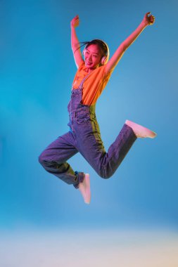 Mavi stüdyo arka planında Neon 'da Asyalı genç kadın portresi. İnsan duyguları kavramı, yüz ifadesi, gençlik, satış, reklam.