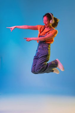 Mavi stüdyo arka planında Neon 'da Asyalı genç kadın portresi. İnsan duyguları kavramı, yüz ifadesi, gençlik, satış, reklam.