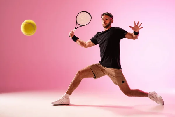 Giovane uomo caucasico che gioca a tennis isolato su sfondo rosa studio, azione e movimento concetto — Foto Stock