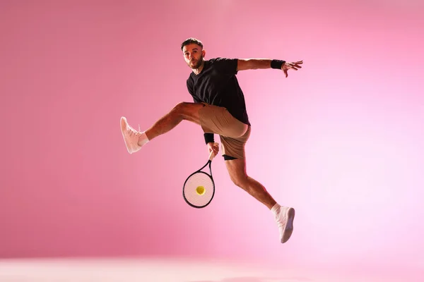 Giovane uomo caucasico che gioca a tennis isolato su sfondo rosa studio, azione e movimento concetto — Foto Stock