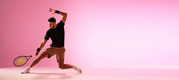Молодий кавказький чоловік грає в теніс ізольовано на рожевому студійному фоні, дії та концепції руху — стокове фото
