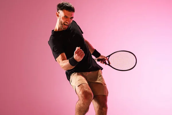 Mladý běloch hraje tenis izolovaný na růžovém pozadí studia, akční a pohybový koncept — Stock fotografie