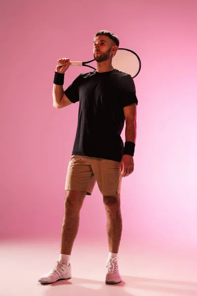 Giovane uomo caucasico che gioca a tennis isolato su sfondo rosa studio, azione e movimento concetto — Foto Stock