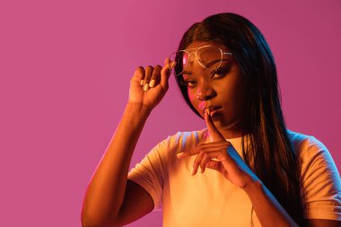 Neon rengi pembe stüdyo arka planında Afrikalı genç kadın portresi. İnsan duyguları kavramı, yüz ifadesi, gençlik, satış, reklam.
