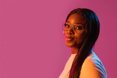 Neon rengi pembe stüdyo arka planında Afrikalı genç kadın portresi. İnsan duyguları kavramı, yüz ifadesi, gençlik, satış, reklam.