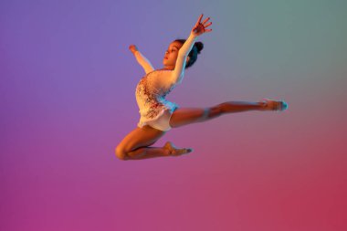 Afro-Amerikan ritmik jimnastikçi, güzel kız neon ışıklarıyla gradyan stüdyoda pratik yapıyor.