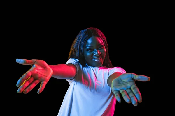 Afrikanische junge Frauen porträtieren auf dunklem Studiohintergrund in Neon. Konzept menschlicher Emotionen, Mimik, Jugend, Verkauf, Werbung. — Stockfoto