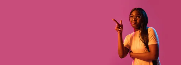 Retrato de mujeres jóvenes africanas sobre fondo de estudio rosa en neón. Concepto de emociones humanas, expresión facial, juventud, ventas, anuncio. — Foto de Stock