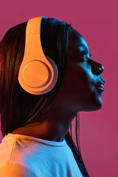 Afrykańskie młode kobiety portret na różowym tle studio w neonie. Pojęcie ludzkich emocji, ekspresji twarzy, młodzieży, sprzedaży, reklamy. — Zdjęcie stockowe