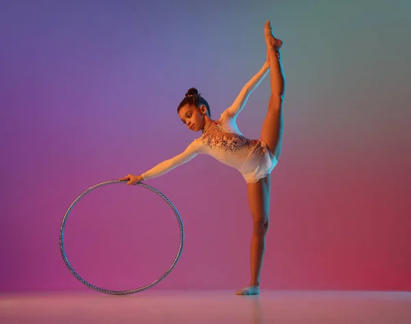 Gimnasta rítmica afroamericana, chica bonita practicando en gradiente fondo de estudio en luz de neón —  Fotos de Stock