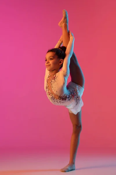 Gimnasta rítmica afroamericana, chica bonita practicando en gradiente fondo de estudio en luz de neón —  Fotos de Stock