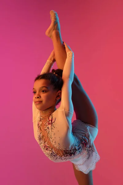 Gimnasta rítmica afroamericana, chica bonita practicando en gradiente fondo de estudio en luz de neón —  Fotos de Stock