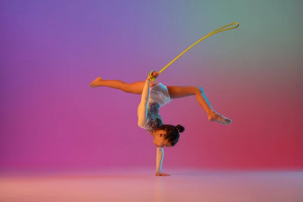 Gimnasta rítmica afroamericana, chica bonita practicando en gradiente fondo de estudio en luz de neón —  Fotos de Stock