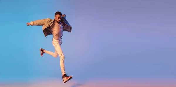 Homem elegante jovem em roupa de estilo moderno rua isolado no fundo gradiente em luz de néon. Modelo na moda afro-americano em livro de visual, músico realizando. — Fotografia de Stock