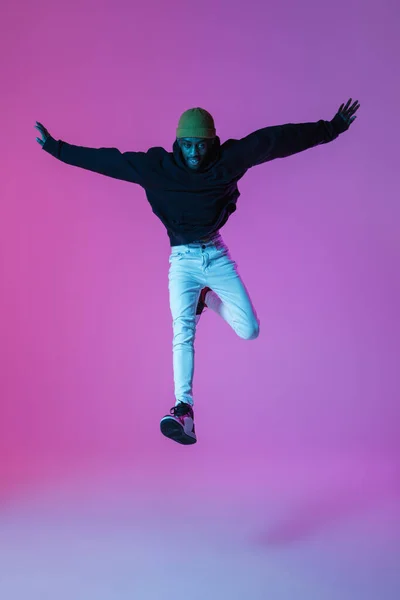 Homem elegante jovem em roupa de estilo moderno rua isolado no fundo gradiente em luz de néon. Modelo na moda afro-americano em livro de visual, músico realizando. — Fotografia de Stock